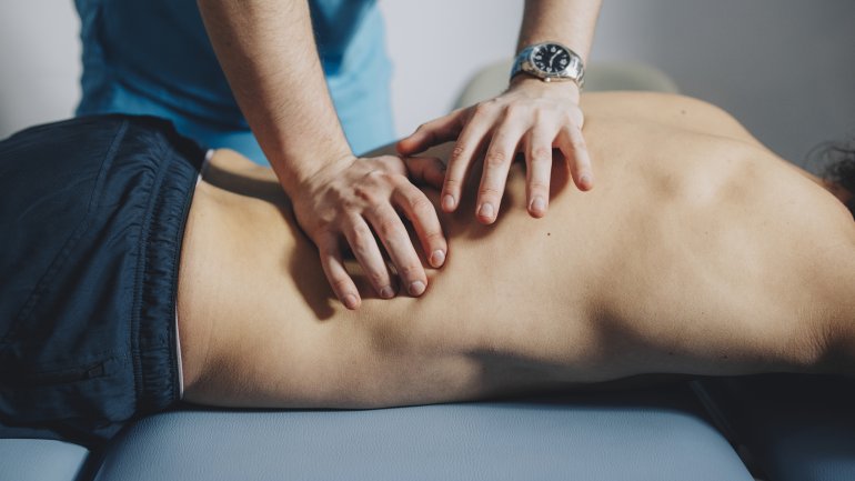 Mann liegt auf der Liege und lässt sich von Physiotherapeuten behandeln