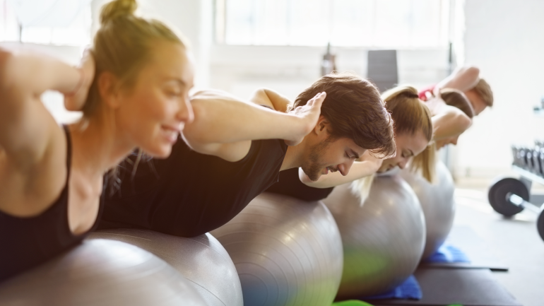 Mehrere Menschen machen Übungen auf dem Gymnastikball