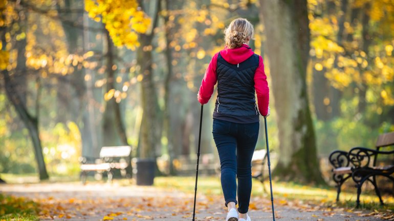 Frau von hinten beim Nordic Walken in herbstlicher Umgebung