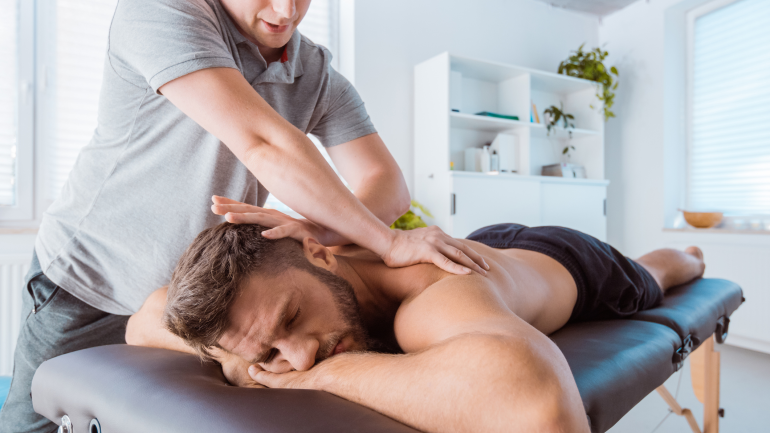 Mann liegt auf der Massagebank und wird massiert