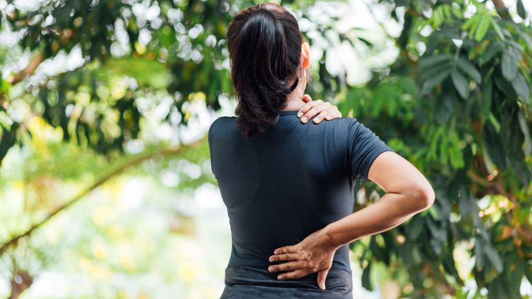 Frau beim Sport im freien, hält sich Rücken und Nacken